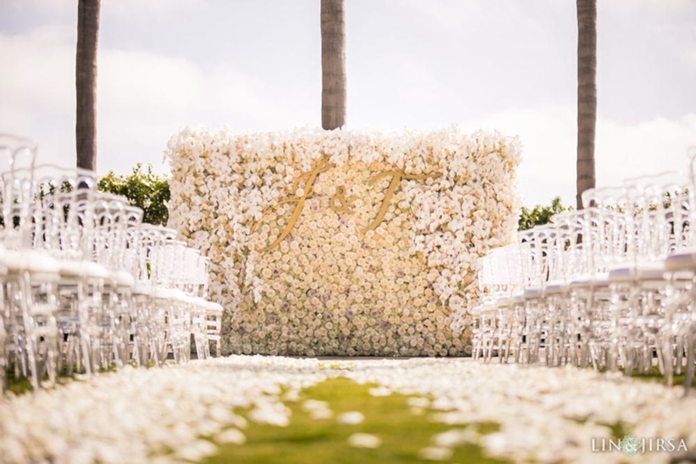 White rose flower wall decorated with a carpet of white rose petals, with white chairs placed on either side of the wedding ceremony aisle at the Park Hyatt Aviara resort in Carlsbad, shot by Lin and Jirsa Los Angeles and planned by Lavish Weddings in San Diego, California White rose flower wall decorated with a carpet of white rose petals, with white chairs placed on either side of the wedding ceremony aisle at the Park Hyatt Aviara resort in Carlsbad, California