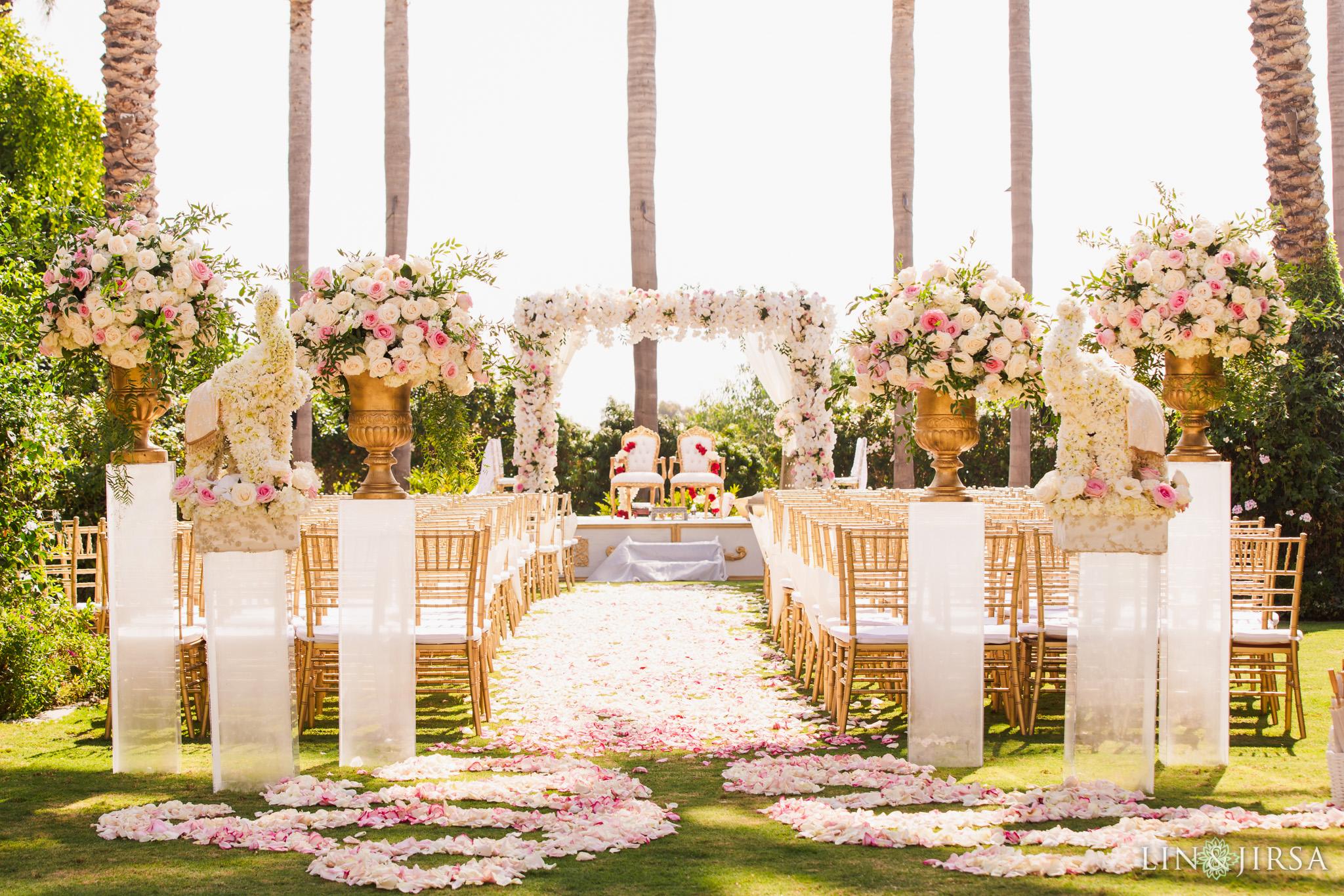 Lavish wedding altar with straw colored chairs and white rose petals carpeting the bridge and groom walkway, under palm trees in Carlsbad, California at the Park Hyatt Aviara Resort Lavish wedding altar with straw colored chairs and white rose petals carpeting the bridge and groom walkway, under palm trees in Carlsbad, California at the Park Hyatt Aviara Resort