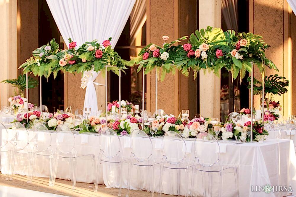 Stately and stylized white tables with delicately adorned roses and ferns on a catering table during a wedding at the San Diego Museum of Art , located in California and shot by famous wedding photographers: Lin and Jirsa and planned by Lavish Weddings Stately and stylized white tables with delicately adorned roses and ferns on a catering table during a wedding at the San Diego Museum of Art , located in California